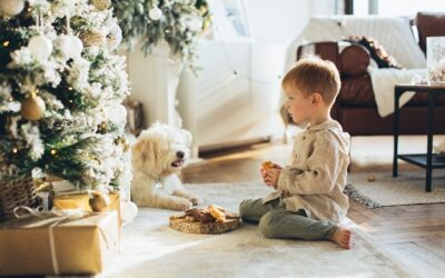 Jongen met hond bij kerstboom en er ligt eten en chocolade op de grond