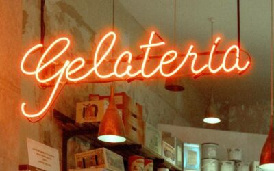 Een neon-bord met het oranje woord Gelateria hangt in een ijswinkel